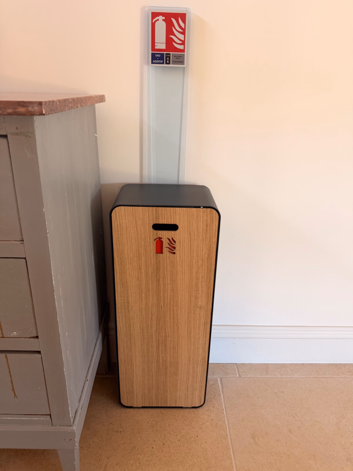 Coffret extincteur en bois posé à côté d'une commode ancienne dans le couloir d'une maison d'hôtes à Saint-Jean-de-Blaignac