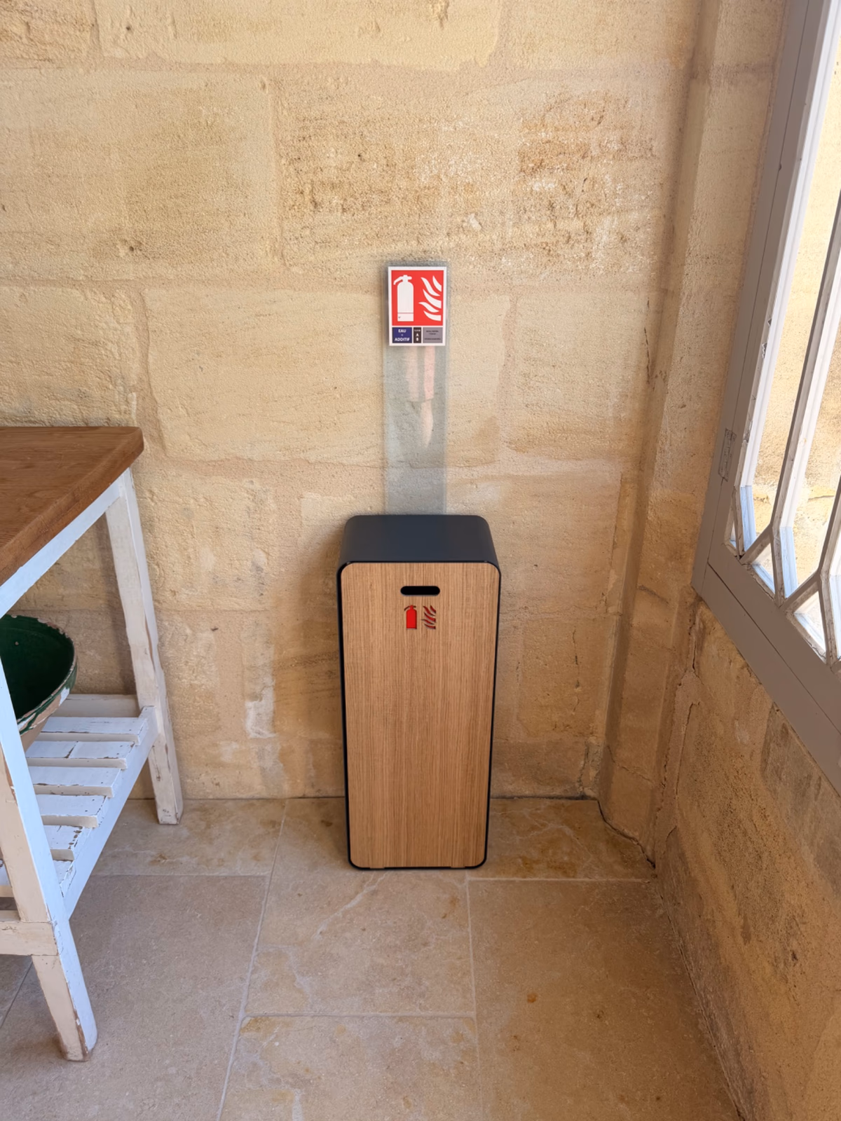 Coffret extincteur design près d'une fenêtre à petits carreaux, intégré au décor d'une maison d'hôtes en Gironde