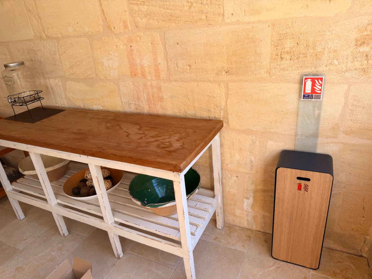 Coffret design en bois intégrant un extincteur à eau, posé contre un mur en pierre dans une maison d'hôtes à Saint-Jean-de-Blaignac