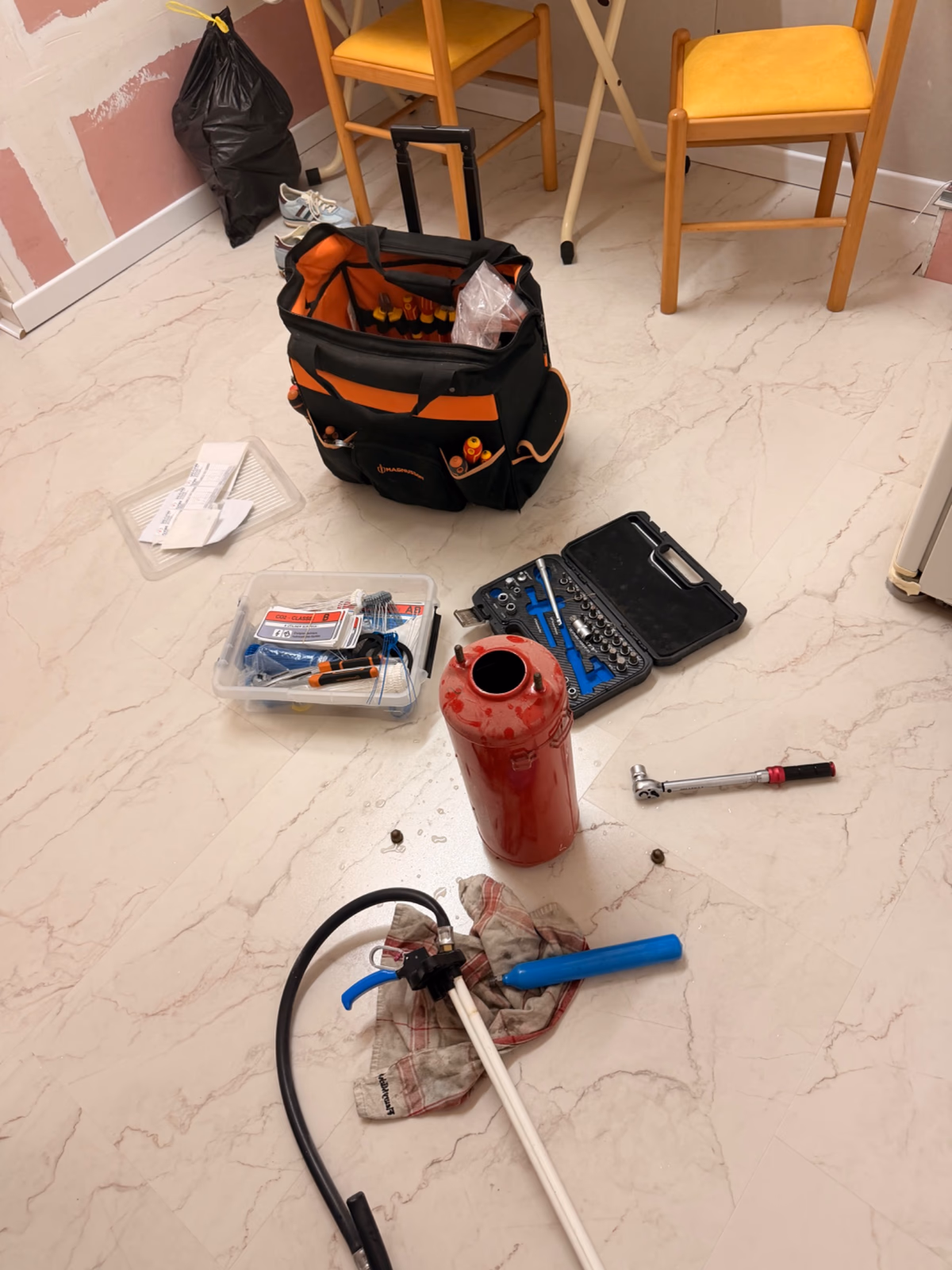 Extincteur CO2 2 kg posé au sol avec la mallette d'outillage du technicien lors de la maintenance annuelle d'une salle de fitness à Royan