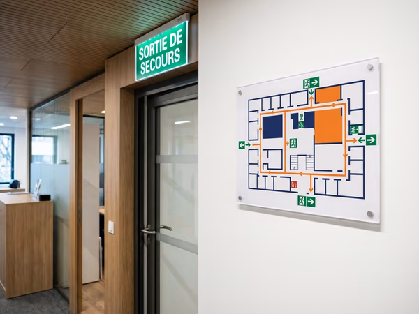 Plan d'évacuation conforme affiché dans un hall d'entreprise